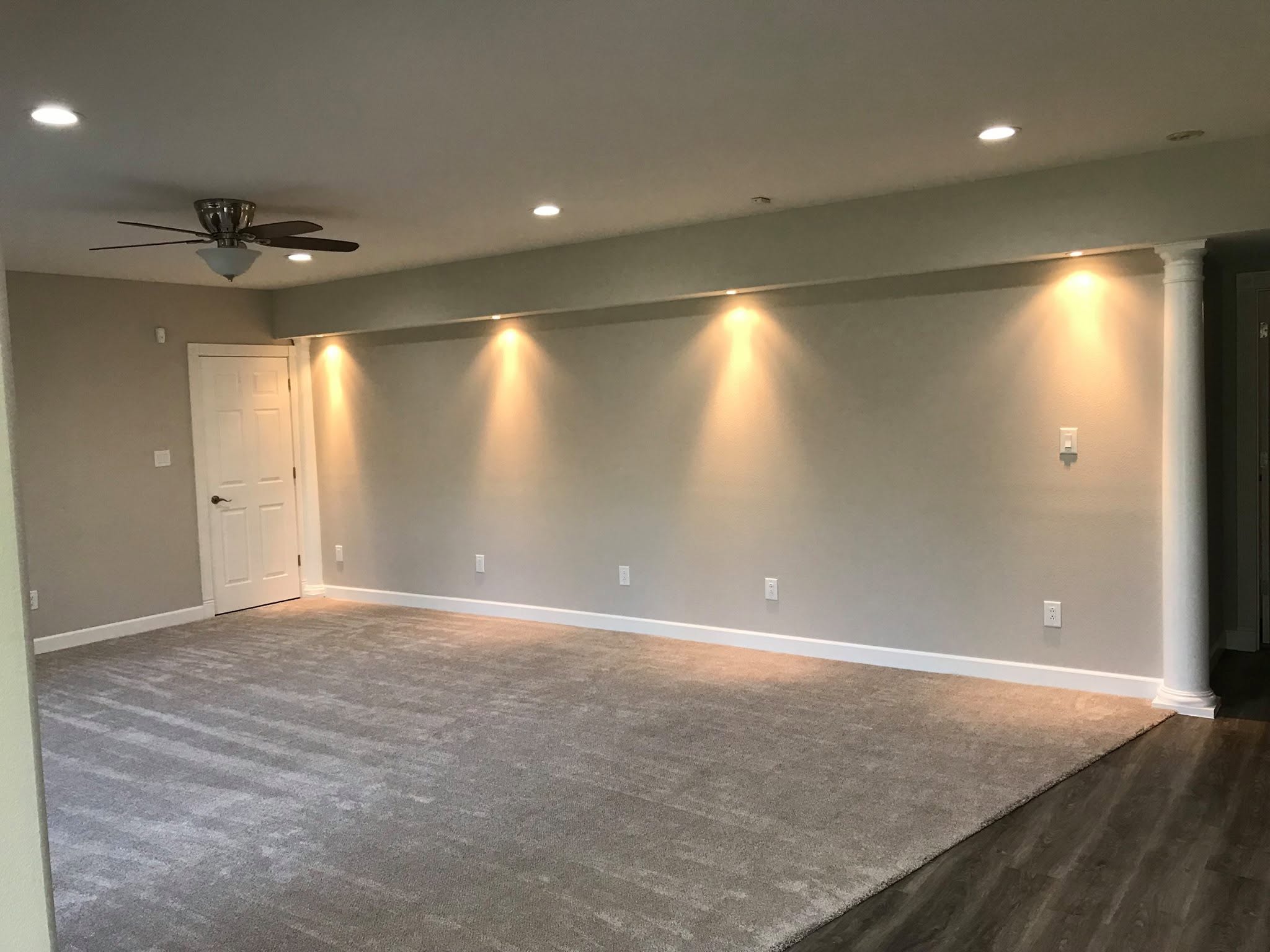 Finished interior remodel by Xemplar Construction with recessed lighting, painted walls, carpet, and wood-look flooring